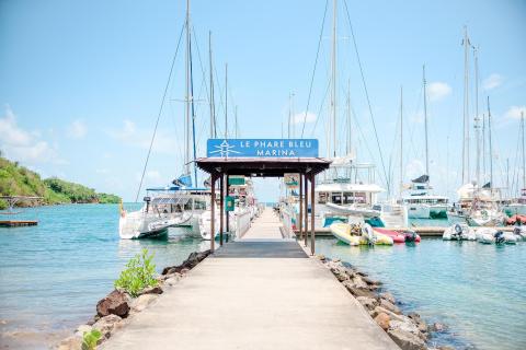 Entrance to Le Phare Bleu Marina with boats and blue skies.