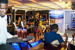 Live band performs at vibrant bar, waiter serving drinks, patron engaged.