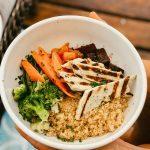 Healthy quinoa bowl with grilled chicken, broccoli, carrots, and sauce