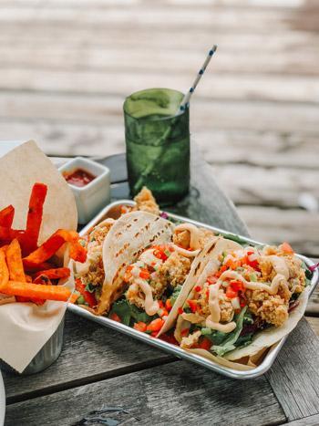 Tacos with possible chicken or fish, red sweet potato fries, and a green drink on a tray