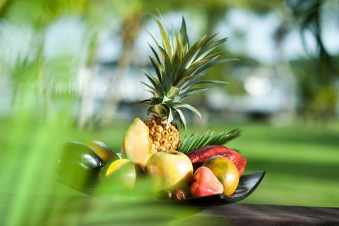 Tropical fruits display with pineapple, mangoes, and papaya on wooden table.