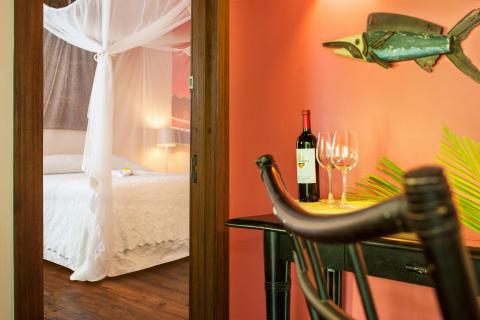 Cozy bedroom with sheer curtains, wine on table, and exotic decor elements.