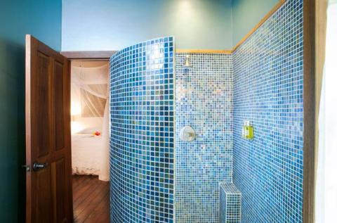 Stylish curved shower with blue mosaic tiles and adjacent cozy bedroom.