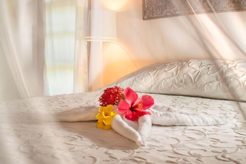 Luxury tropical resort bedroom with white bed and artistic towel art.