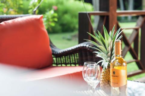 Outdoor patio with pineapple, Garofoli Macrina wine, and lush garden.