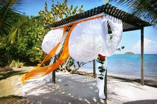 Romantic beach venue setup with white floral decor and sea backdrop
