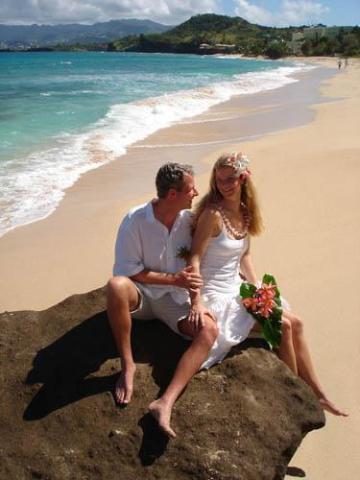 Newlywed couple in white clothing enjoying a serene beach setting