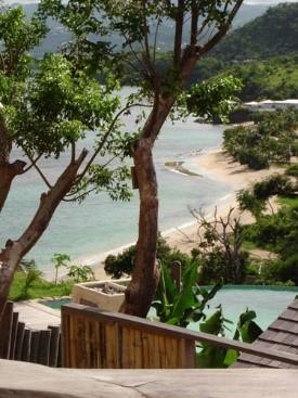 Scenic tropical beach view from a balcony with lush greenery and clear waters.