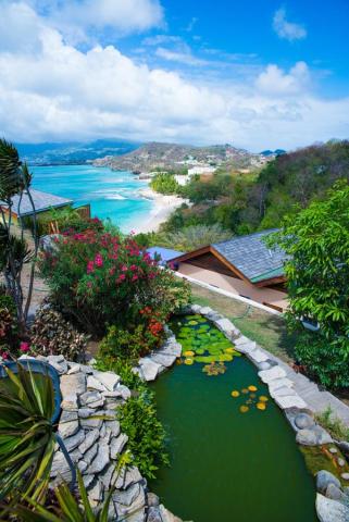 Vibrant coastal scene with garden, pond, beach, and resort under a clear sky