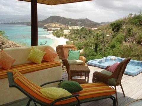 Luxurious patio with hot tub overlooking a scenic coastline and turquoise sea
