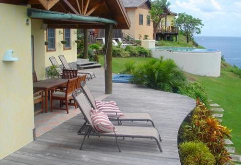 Coastal outdoor lounge with pool, ocean view, and overcast sky.