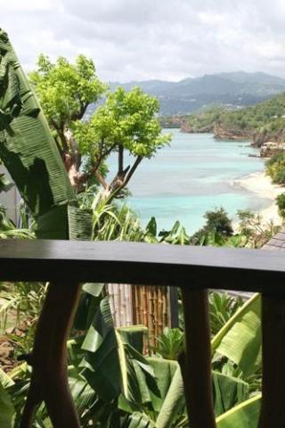 Scenic tropical bay view with lush greenery, sandy beach, and mountain backdrop