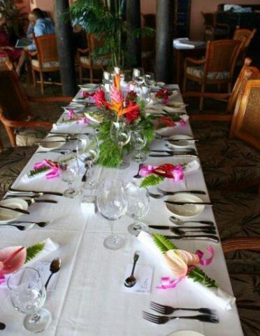 Elegant restaurant dining table with tropical flowers and white tablecloth