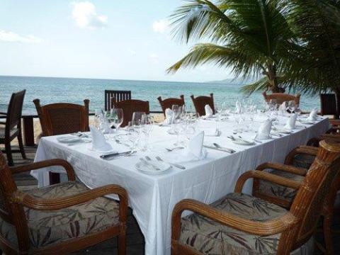 Elegant seaside dining setup with white tablecloth and rattan chairs.