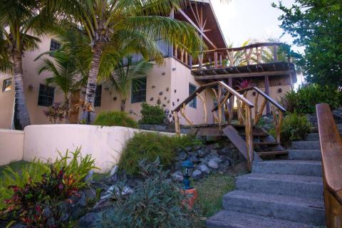 Tropical villa with thatched roof, palm trees, and lush garden in a serene setting