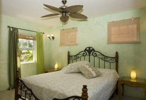 Cozy bedroom with double bed, wrought iron frame, and light green decor.