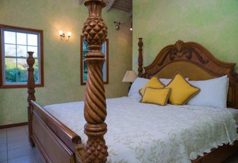 Traditional bedroom with carved wooden bed and green textured walls.