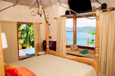 Luxury bedroom with ocean view, wooden bed frame, and tropical decor