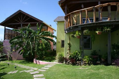 Lush garden with pink and green houses, tropical plants, and stone pathway