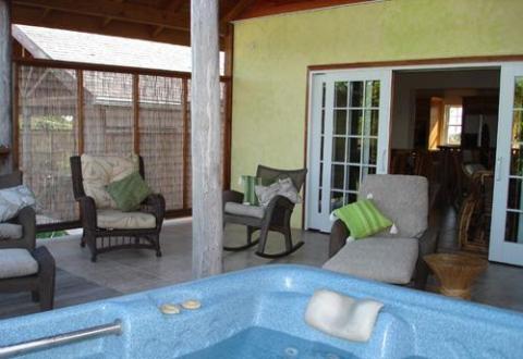 Cozy outdoor living space with hot tub, plush seating, and open French doors