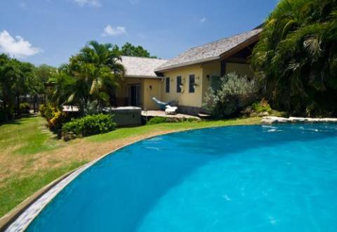 Inviting backyard with curved pool, green lawn, and hammock on sunny day