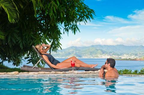 Couple enjoys sunny resort with pool and scenic coastal view