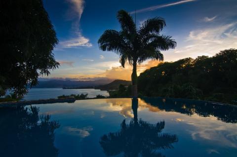 Tranquil infinity pool with mountain view at sunset under colorful skies