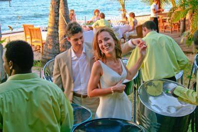 Joyful beach wedding scene with dancing couple and live steel drum music.