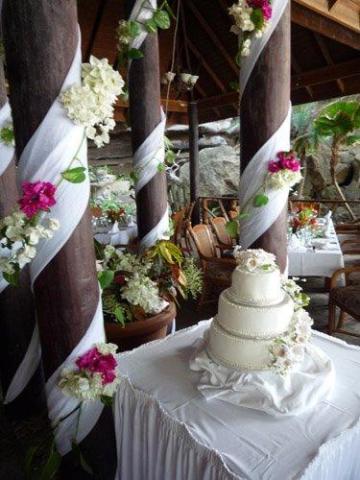 Rustic wedding cake setup with floral decorations in a pavilion