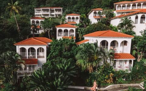 White Mediterranean buildings with orange roofs in lush tropical setting