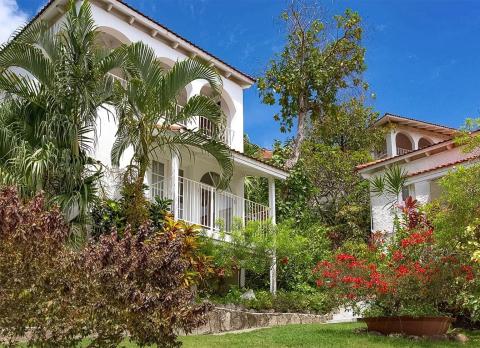 Tropical houses with red roofs and lush gardens under a clear blue sky
