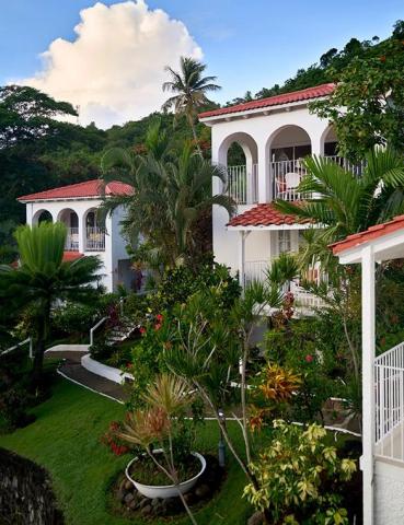 Tropical resort with white buildings and red tile roofs surrounded by palm trees