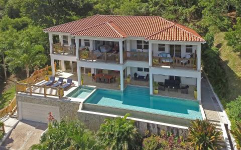 Luxurious two-story house with a pool and lush greenery in a tropical setting
