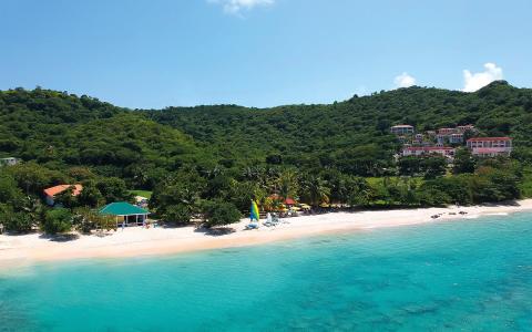 Tropical beach with white sand, turquoise water, umbrellas, and hillside resorts