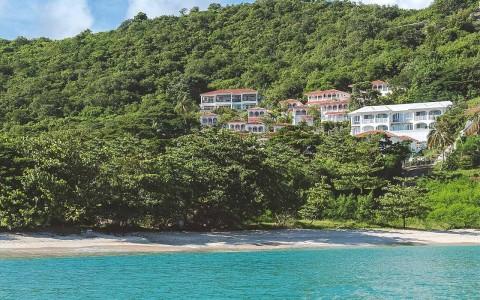 Tropical beach with lush hillside villas overlooking calm sea