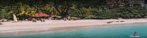 Tropical beach with turquoise waters, colorful umbrellas, and paddleboards