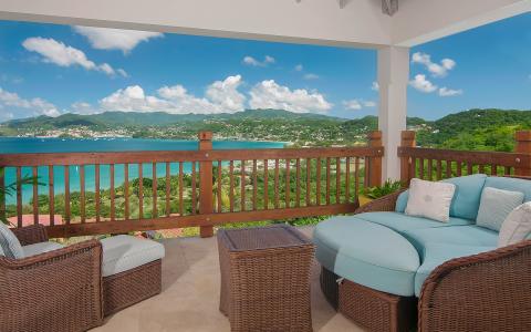 Scenic porch view overlooking tropical bay with cozy blue sofa and lush landscape."
