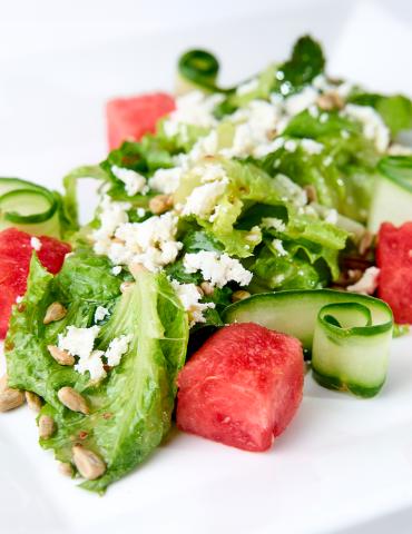 Fresh watermelon, cucumber, feta cheese, and lettuce salad with sunflower seeds.