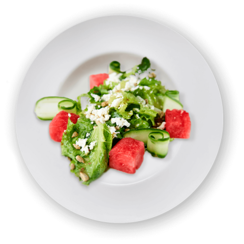 Fresh watermelon salad with feta, cucumber ribbons, nuts, on a white plate