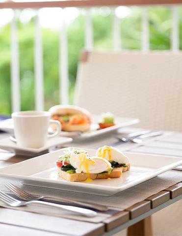 Outdoor brunch with Eggs Benedict and coffee on a table, garden view.