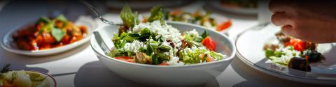 Variety of fresh salads and tomato dish on table, mealtime setting.