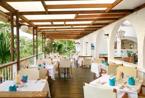 Elegant outdoor restaurant dining area with wooden pergola and lush tropical backdrop