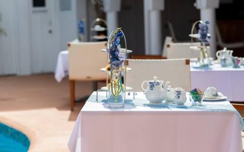 Luxurious outdoor dining setup beside a pool with fine china and glass centerpiece