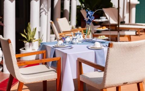 Elegant outdoor dining setup with blue tablecloth and floral tea set.