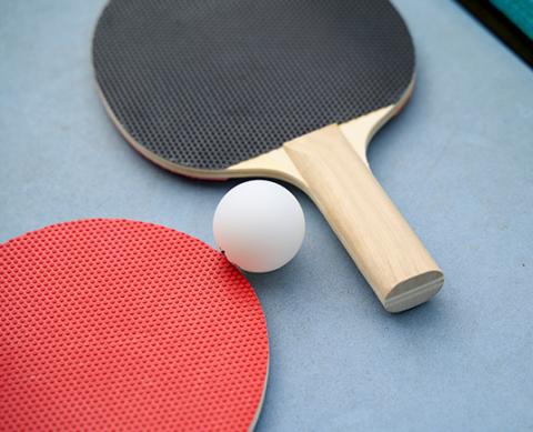 Two table tennis paddles, one red and one black, with ball on blue table