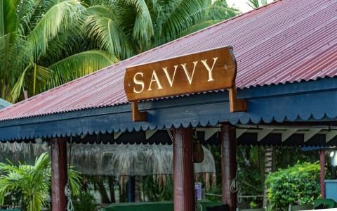 SAVVY sign over red-roofed entrance in lush tropical setting