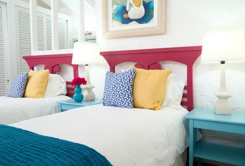 Colorful twin bedroom with polka dot pillows and beach-themed art