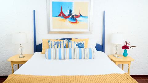 Nautical themed bedroom with striped sheets and sailboat painting.