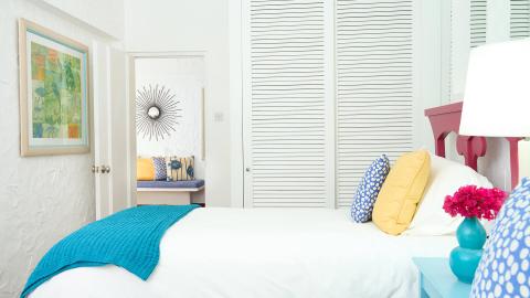 Colorful bedroom with vibrant pillows, turquoise throw, and artful decor