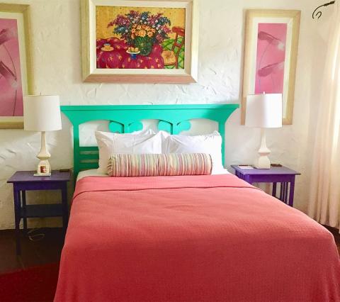Brightly decorated bedroom with coral bedspread and vivid turquoise headboard.